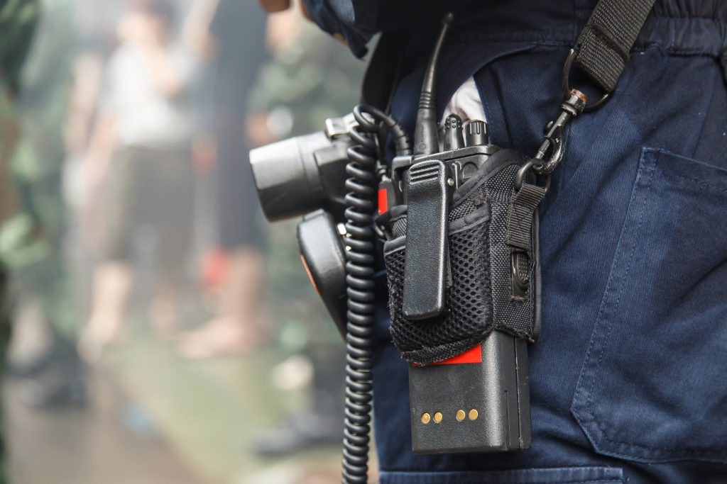 Closeup of a two-way radio inside a radio carrying case that is strapped around an emergency responder.