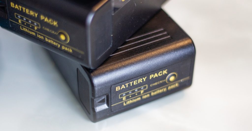 Two identical black lithium-ion battery packs stacked on top of one another against a white background.