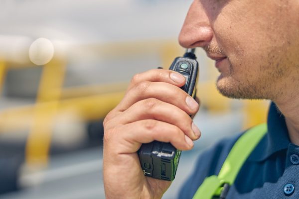 An emergency worker holding a two-way radio up to his mouth getting ready to speak to someone on the other end.