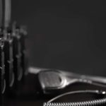 A row of five two-way radios sitting on a black table next to a wired walkie-talkie over a black background.