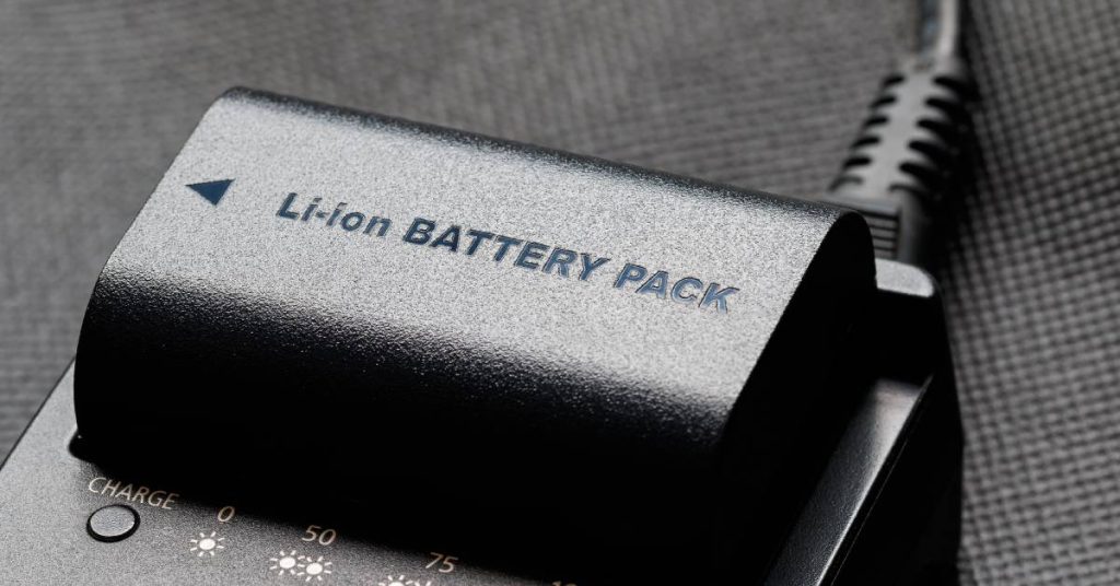 A close-up of a lithium-ion battery pack sitting in a charger with different charge level indicators printed on it.