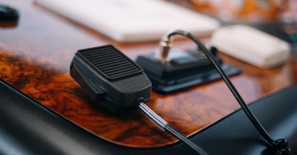 The navigation panel on a ship with a wood grain design is connected to a two-way radio and other instruments.