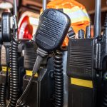 The backseat of an emergency responder vehicle contains a group of black, two-way communication radios.